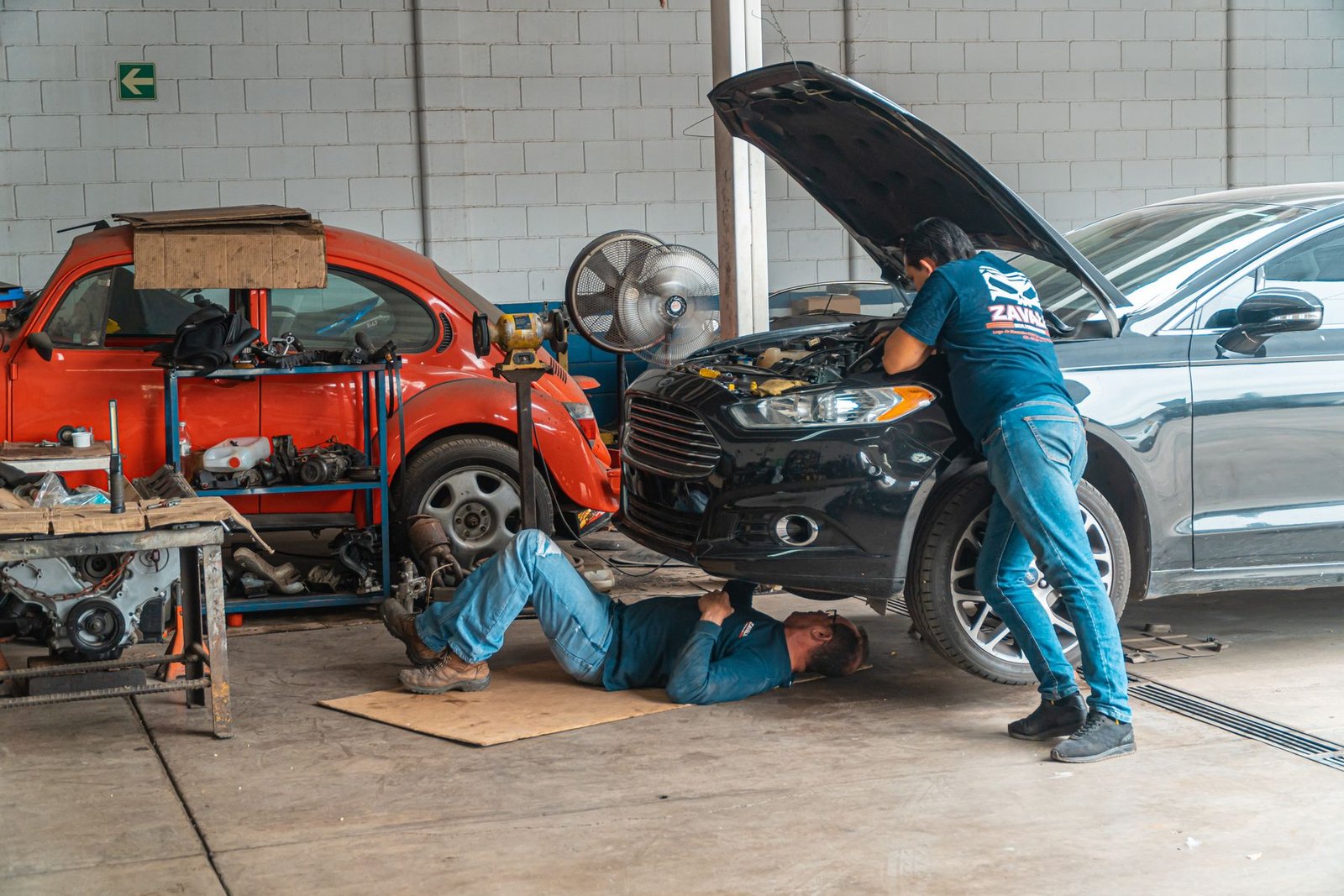 Mechanics servicing a car in an automotive workshop